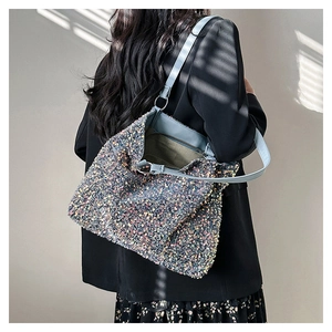 Détail d'un sac à paillettes brillant avec bandoulière en cuir bleu et anneaux dorés