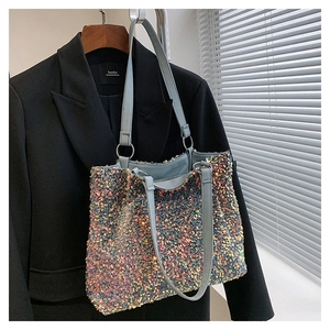 Détail d'un sac cabas à paillettes colorées avec bandoulière bleu clair sur un blazer noir