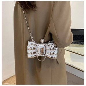 Detail of silver bow clutch bag with crystal centerpiece and pearl clasp on suit