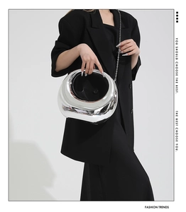 Close-up of a silver crescent acrylic evening bag with metallic finish and chain strap