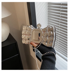 Detail of silver bow-shaped acrylic evening bag with pearl clasp and chain strap