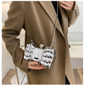Detail of silver bow clutch featuring a square gemstone and pearl clasp with bead chain