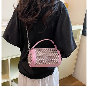 Detailed view of pink cylindrical crossbody bag with silver studs and chain strap