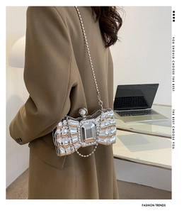 Chic silver bow-shaped clutch featuring a large central crystal and a pearl clasp