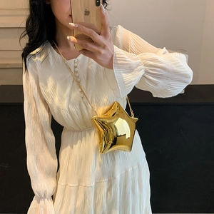 Nahaufnahme einer goldfarbenen Abendtasche in Sternform mit eleganter Metallkette