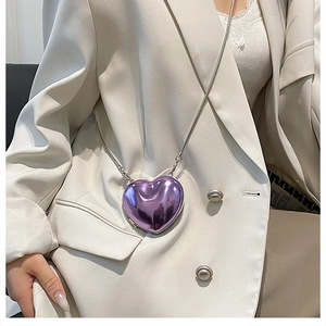 Detailed view of mini purple heart acrylic crossbody bag with silver snake chain on a model