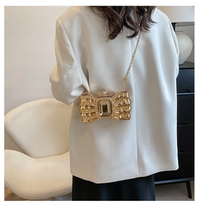 Detail of gold bow-shaped evening clutch with crystal and pearl on a crossbody chain