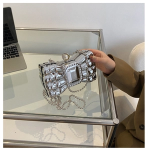 Detailed view of silver bow-shaped evening clutch with pearl clasp and metal chain strap