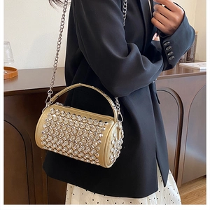Close-up of a sparkling gold rhinestone cylinder bag with a metal chain and handle