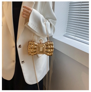 Detail of golden bow-shaped evening clutch with crystal jewel and pearl clasp on chain