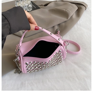Detailed view of pink barrel bag with silver studs and chain strap on white fabric