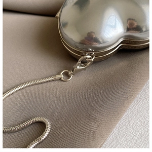 Detail of silver heart-shaped acrylic mini bag with sleek snake chain strap