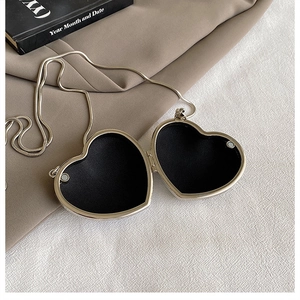 Detailed view of silver heart-shaped mini bag with open magnetic clasp and black lining