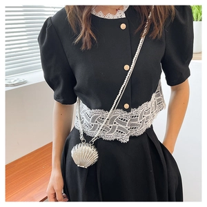 Detail of silver shell-shaped mini bag with pearlescent chain strap worn by a model