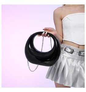 Detail of glossy black crescent bag with hollow handle and silver chain strap