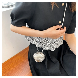 Close-up of shell-shaped crossbody bag featuring pearl chain and metallic finish details