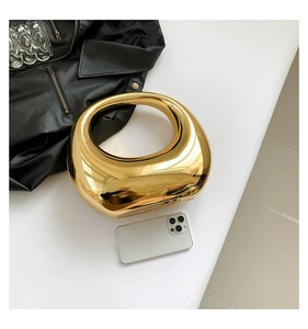 Detail shot of golden acrylic hard-shell handbag with sleek metallic ring handle for size reference