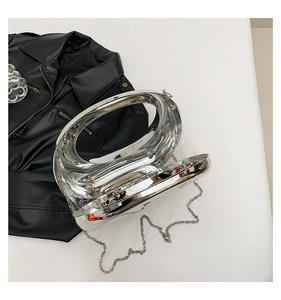 Close-up of a silver acrylic moon-shaped clutch with a metal chain on black leather