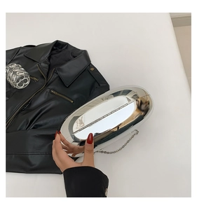 Detail of silver mirror acrylic capsule clutch with sleek metal chain on leather
