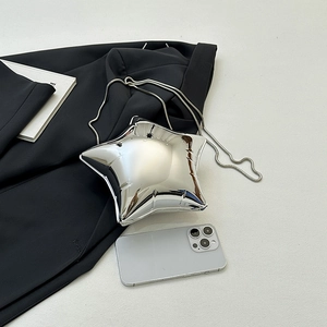 Detailansicht der silbernen sternförmigen Acryl-Clutch mit Kette auf einem Blazer