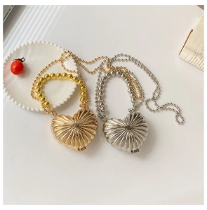 Macro shot of heart-shaped metal mini bags with radial texture and golden bead handle