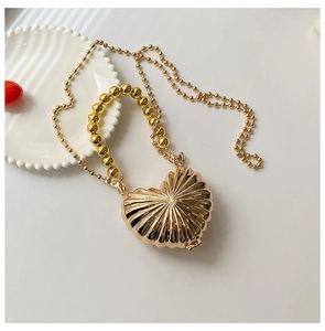 Detail of gold heart-shaped evening clutch with sunburst texture and beaded handle