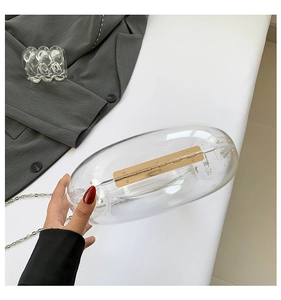 Detail of transparent acrylic crescent evening bag with gold hinges and silver chain