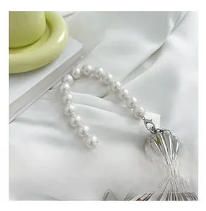 Detail of silver heart-shaped metal bag with pearl handle and textured surface