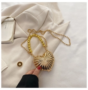 Detail of gold heart mini evening bag with metallic texture and beaded handle