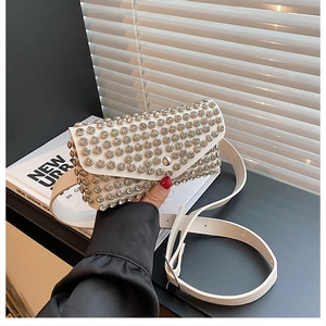 Détail d'un sac bandoulière blanc crème orné de strass brillants et d'une fine bandoulière