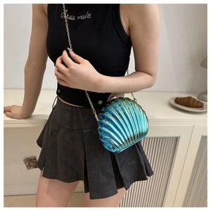 Lifestyle shot of a blue shell-shaped evening clutch with a golden chain strap