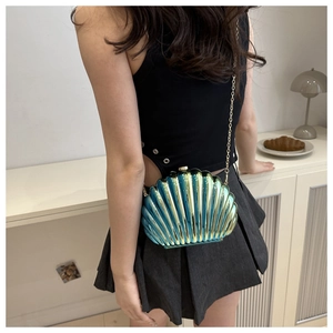 Detailed shot of a shell-shaped evening bag in cyan gradient finish with gold chain