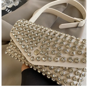 Détail du sac bandoulière crème avec strass scintillants et boucle dorée élégante