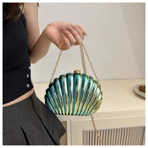 Detail of shell-shaped clutch bag with gradient teal metallic finish and gold chain strap