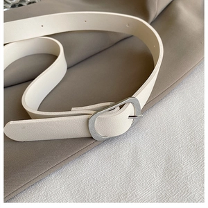 Gros plan sur une ceinture fine minimaliste en cuir blanc crème avec boucle argentée