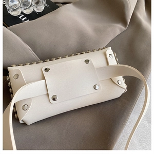Détail du sac banane en cuir crème avec clous argentés et large bandoulière