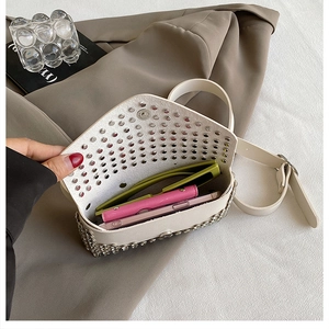 Détail du sac ceinture beige clouté montrant la capacité intérieure avec accessoires