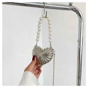 Detail of silver heart-shaped metal mini bag with pearl handle and radial texture