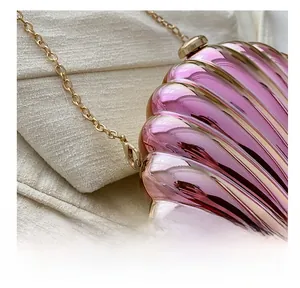 Detail of gold metal hook and chain on pink shell-shaped evening bag with metallic finish