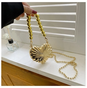 Detail of gold heart-shaped evening bag with pleated metallic finish and beaded handle
