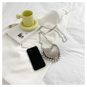 Detail of silver heart-shaped mini metal clutch bag with radial texture and beaded chain
