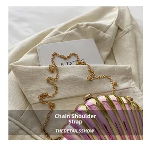 Detail of pink and gold shell-shaped clutch bag with thin gold chain shoulder strap