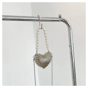 Detail of heart-shaped silver metal mini bag with elegant pearl handle and chain strap