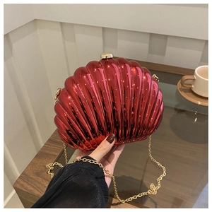 Detail of red shell-shaped evening clutch with gold chain strap and textured finish