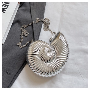 Detailed view of a nautilus shell-shaped evening bag with a silver metallic finish and chain