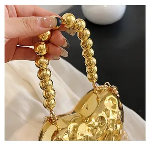 Close-up of golden heart-shaped evening bag with a hammered texture and beaded handle