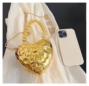 Compact gold heart-shaped acrylic clutch with hammered texture and beaded handle