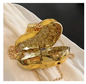 Detailed view of gold irregular evening bag with bee clasp and wrinkled metal texture