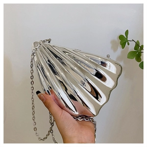 Detail of silver shell-shaped acrylic clutch with metallic mirror finish and chain