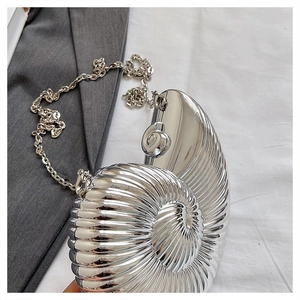Detail of silver nautilus-shaped clutch bag with spiral metallic texture and chain